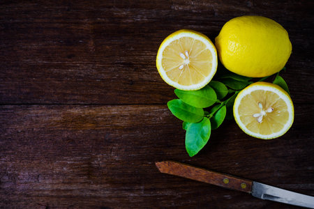 Fresh slice lemons with leaves on wooden background.