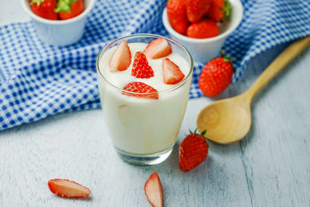 Healthy strawberry yogurt, Delicious refreshing glass of ripe red fresh strawberries and cream or creamy yoghurt garnished for a tasty dessertの写真素材