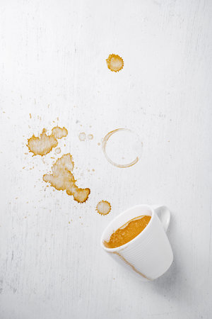 Overturned cup of coffee on white wooden background.の写真素材