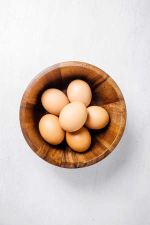 top view of eggs in bowl on white wooden background.の写真素材