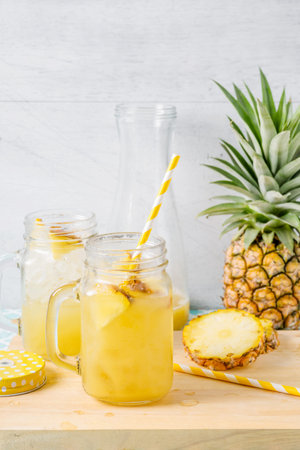 Pineapple slices and juice in glassware on wooden table