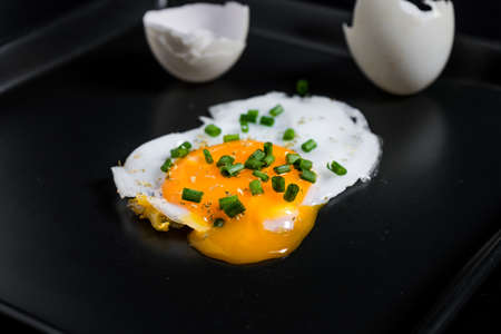Fried eggs with onion in black panの写真素材