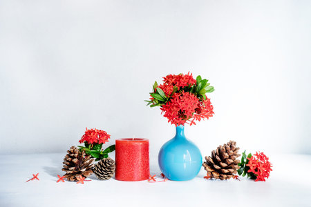 Red ixora flower in blue ceramic vase and red  candle on wood table