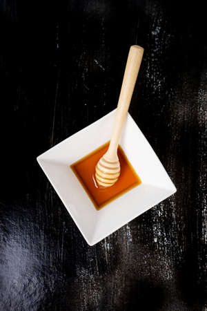 Organic Honey with Honey Dipper in ceramic bowlの写真素材