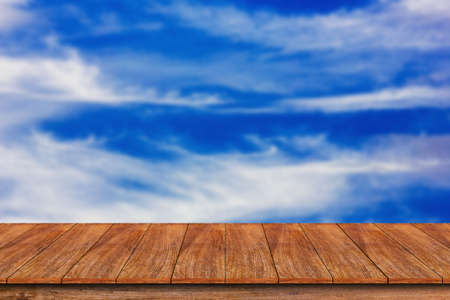 Wood table top on blurred blue sky background , can be used for display or montage your productsの写真素材