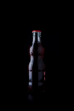 Bottles with red drink on black background.