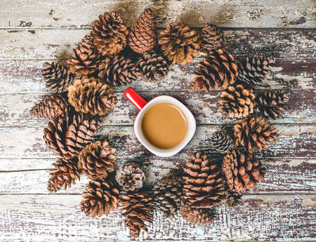 Cup of coffee and pine cones on rustic wooden backgroundの写真素材