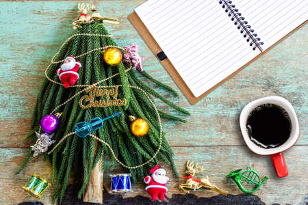 Decorated Christmas tree and cup of coffee on wooden backgroundの写真素材