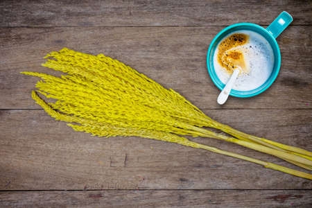 Cup of coffee and grass flowers on wooden backgroundの写真素材
