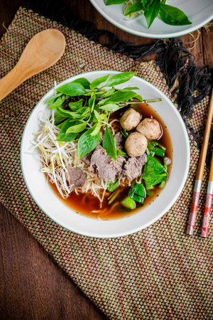asian noodle soup with beef meatball with fresh vegetable on wood table vintage style, street food,...