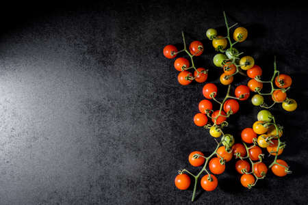 Fresh cherry tomatoes on black wooden backgroundの写真素材