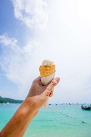 Ice cream cone held up to the hot summer skyの写真素材