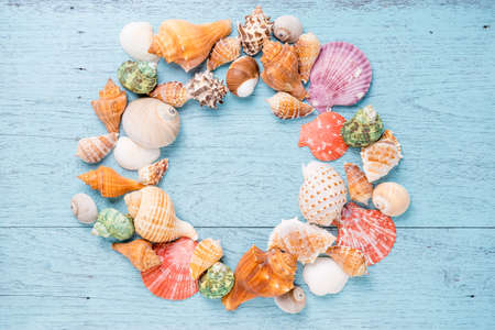 Frame with seashells on blue wooden background. Sea flat lay for mock up. top viewの写真素材