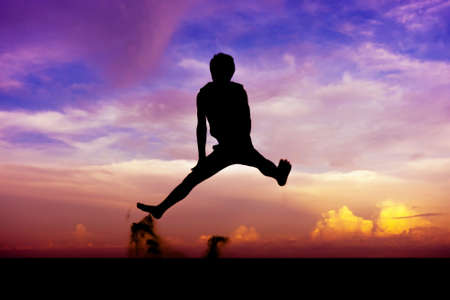 Silhouette man of having fun jumps on sunsetの写真素材