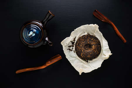 Tea pot and green dry tea on black tableの写真素材