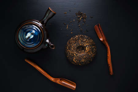 Tea pot and green dry tea on black tableの写真素材