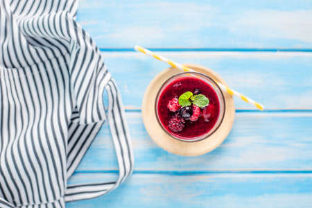 Berry Smoothie with Mint, black currant, red currant, raspberry and blueberry on blue wooden tableの写真素材