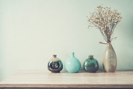 Decorative ceramic vases on wooden table, vintage tone
