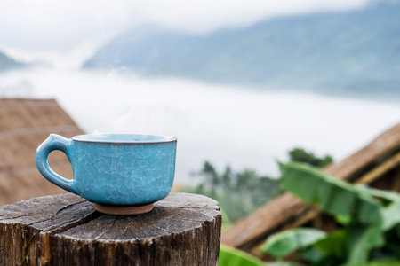 Hot Coffee cup on the wooden and Homestay camping  at Doi Luang Chiang Dao background.