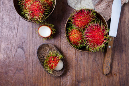 Fresh rambutans in a woodean bowl on wooden background.の写真素材