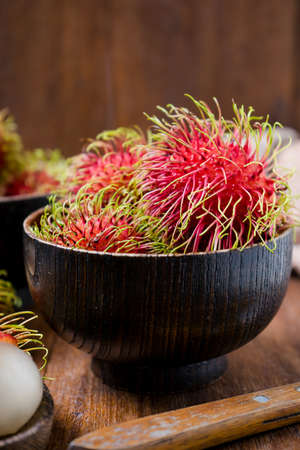 Fresh rambutans in a woodean bowl on wooden background.の写真素材