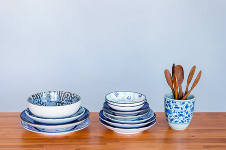 Stack of ceramic tableware on wooden table.