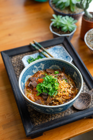 Rice noodles with spicy pork sauce (Nam ngiao) on black table, Thai food.