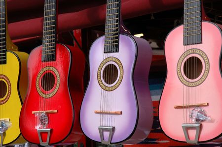 Four colourful toy guitars hang outside a small shop の写真素材