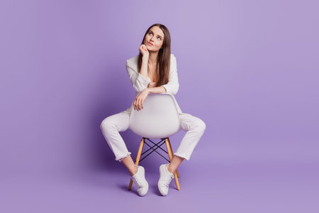 Close up portrait of charming smart lady sit chair hand chin look camera posing on violet wall