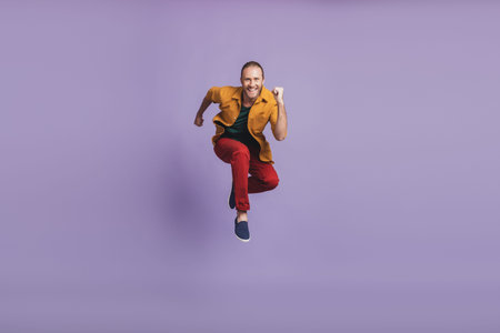 Close up portrait of sporty active guy with beard hold netbook jump run