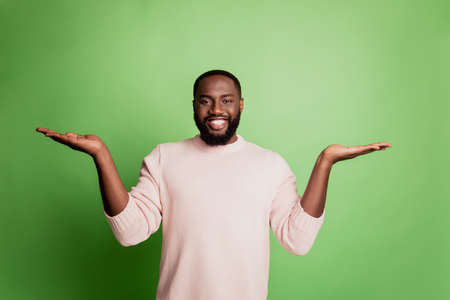 Photo of happy joyful man two palms hold empty space wear white shirt over green backgroundの写真素材
