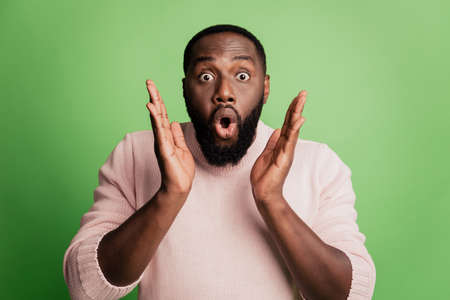 Photo of excited shocked man palms near omg face open mouth wear white shirt over green backgroundの写真素材