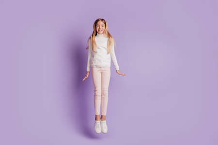 Photo of cheerful sporty lady jump enjoy fun wear white jumper posing on purple backgroundの写真素材