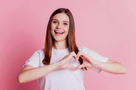 Cheerful positive romantic lovely girl is gesturing a heart with fingersの写真素材