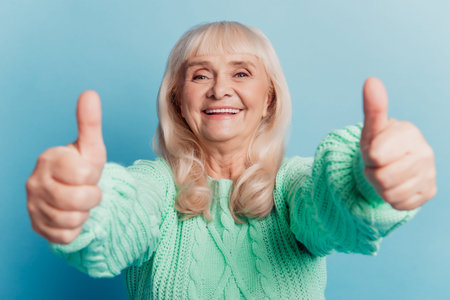 Old mature lady show double thumb-up isolated on blue background