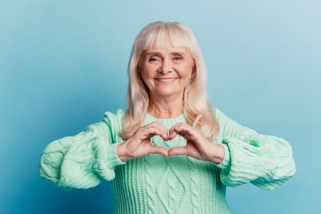 Photo of old woman show heart fingers love symbol isolated over blue background