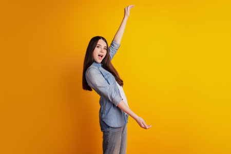 Young woman isolated yellow background holding copyspace measure size