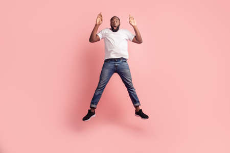 Portrait of excited crazy careless man jumping on pink backgroundの写真素材