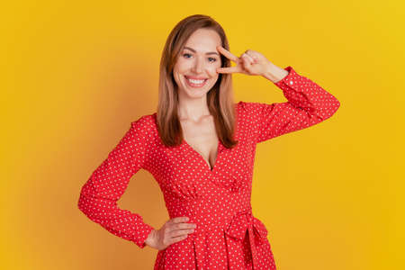 Portrait of charming lovely girl show victory sign isolated on backgroundの写真素材