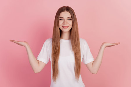 Young woman two hands holding copyspace imaginary advertisement products on pink wall