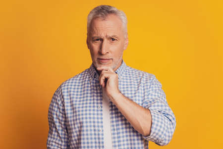 Aged man with hand on beard looking up thinkingの写真素材