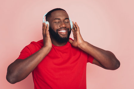 Young african american man enjoy music headset over pink background