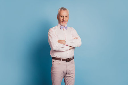 Photo of aged businessman with crossed arms on blue background