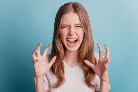 Portrait of angry furious outraged teen girl crazy face shout on blue background