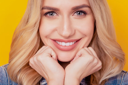 Portrait of cheerful tempting lady fists cheeks look camera beaming white smile on yellow background