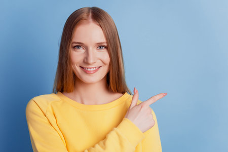 Portrait of cheerful positive adviser girl direct forefingers empty space on blue background