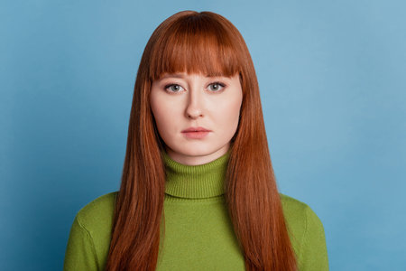 Portrait of charming focused girl look camera on blue background