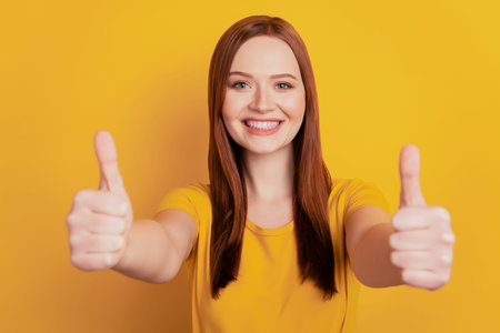 Beautiful young smiling woman give thumb up isolated on yellow background