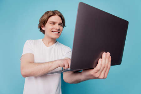 Portrait of guy influencer holding laptop working isolated over blue backgroundの写真素材