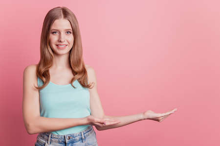 Portrait of positive reliable lady hand demonstrate empty space on pink backgroundの写真素材